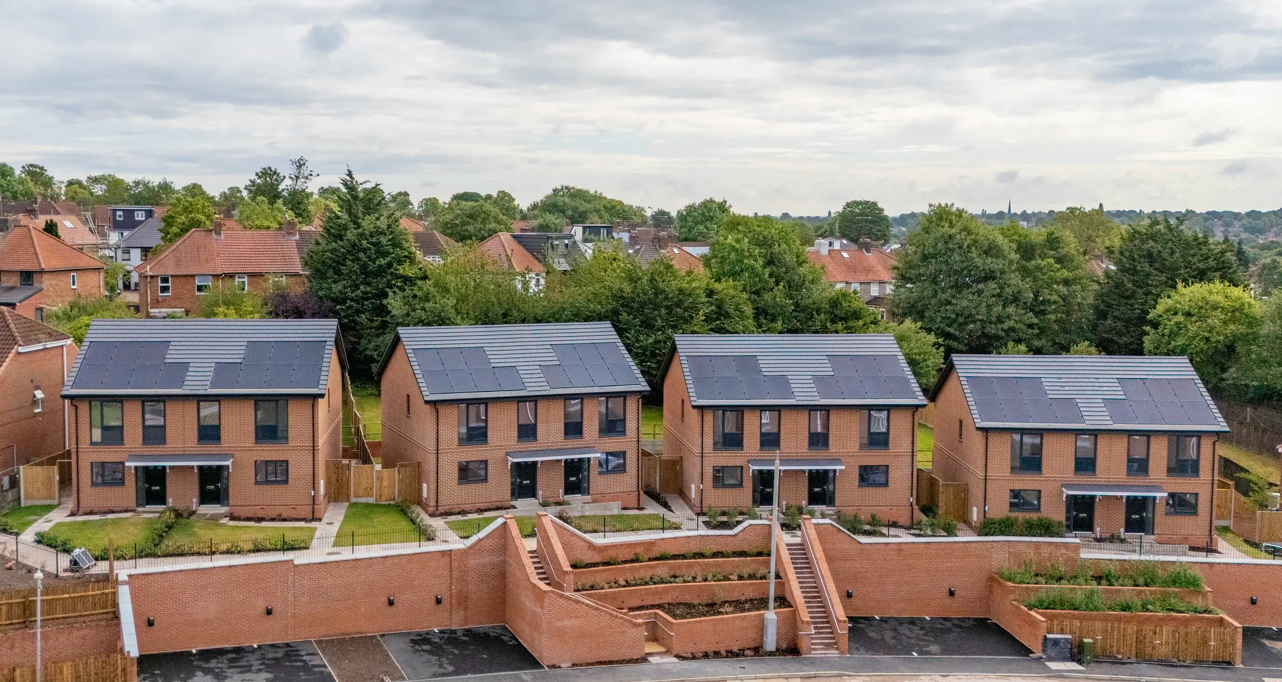 Aerial view of new affordable homes with solar panels at Barnesville Close, Small Heath, stepped above tiered retaining walls
