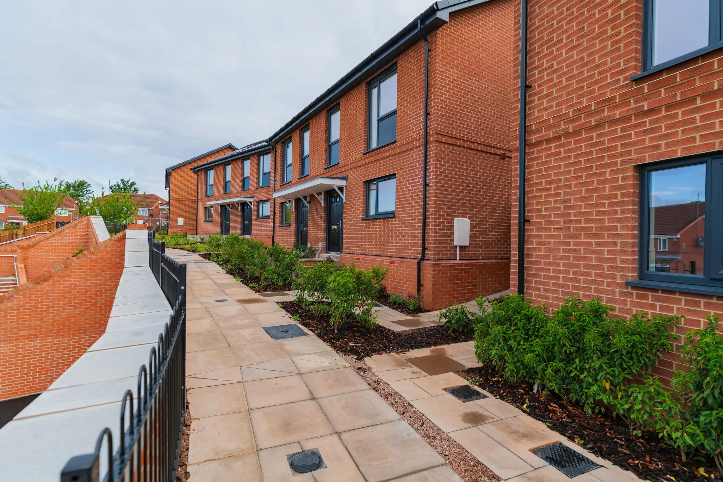 Paved footpath with railings running alongside the new terrace of homes